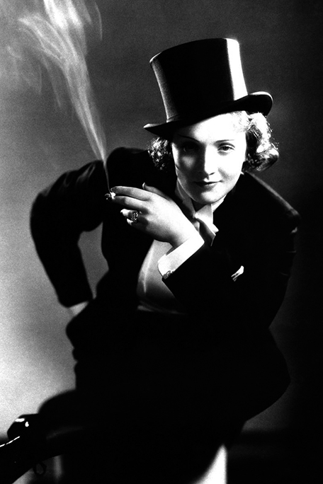 Fotografía de Marlene Dietrich vestida de hombre y fumando. Fotografía en blanco y negro.