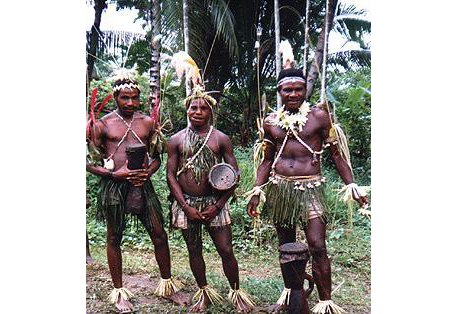 Picture of three members of the Sambia tribe in the jungle, carrying drums.