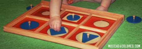 Baby playing to fit pieces on a board without following the shapes (rules).